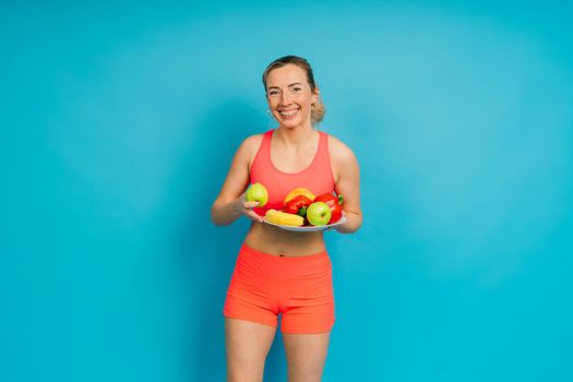 Healthy eating, happy woman with fruits and vegetables is eating an apple