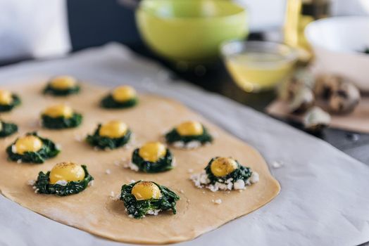 Step by step the chef prepares ravioli with ricotta cheese, yolks quail eggs and spinach with spices. The chef prepares the filling on the dough