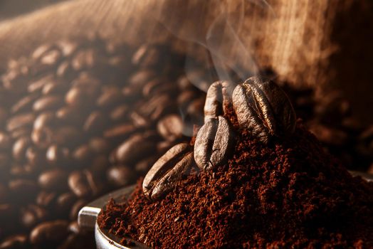 ground coffee poured into the holder on which the grains of roasted, fragrant coffee lie. on the background of fried grains