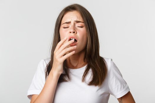 Portrait of girl with allergy sneezing, cover mouth with hand. Sick woman standing over white background.