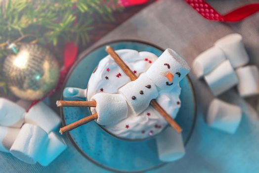 Christmas background with a marshmallow man lying in a mug with cocoa, in the background a Christmas tree with toys, a garland and gifts