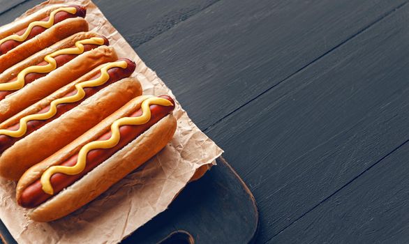 Barbecue Grilled Hot Dogs with  yellow American mustard, On a dark wooden background