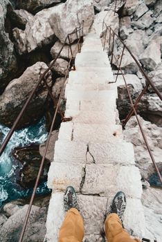 Traveler man crossing the river on a stone staircase, point of view.