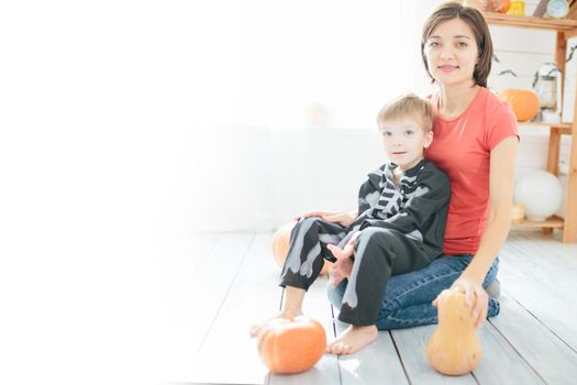 Happy family of mother and children prepare for Halloween in decorate the home .