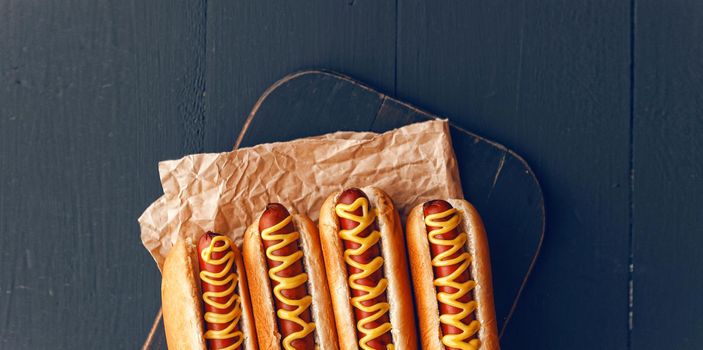 Barbecue Grilled Hot Dogs with  yellow American mustard, On a dark wooden background