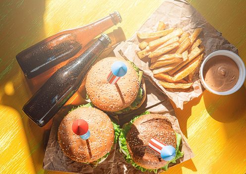 three fresh and juicy burgers with American flag-style fireworks inserted into them. bbq concept picnic to celebrate independence day