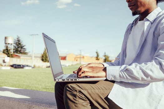 Close up of afro american hands typing on laptop on park