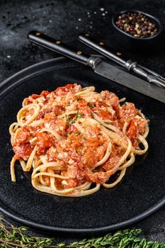 Trendy Feta pasta with Oven baked cherry tomatoes and cheese on a plate. Black background. Top view.