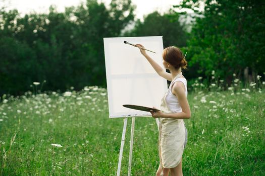 woman artist paints on easel in nature landscape. High quality photo