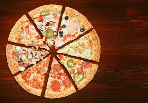 mix of eight different pizzas on a wooden background. menu concept of choice and diversity