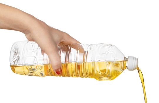 Hand of woman pouring cooking oil from plastic bottle. Isolated on white background. Close up.