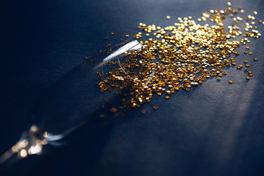 concept spilled white wine or champagne. end of the party. a glass of wine lying on a table in it gold stars symbolizing spilled wine