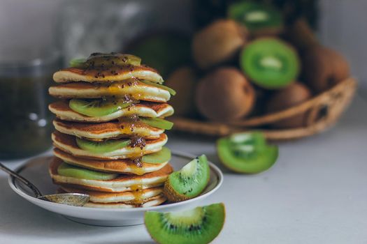 Plate of pancakes dripping with kiwi jam with kiwi pieces. Shrovetide Maslenitsa Butter Week festival meal. Shrove Tuesday. Pancake day