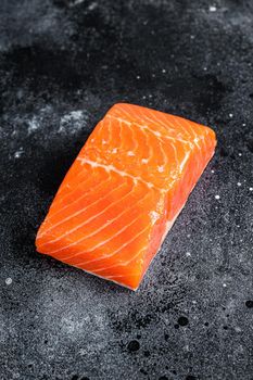 Raw salmon fillet steaks on kitchen table. Black background. Top view.