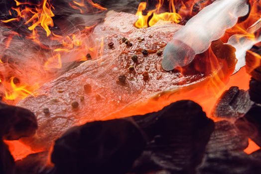 raw marbled beef steak with coals and smoke