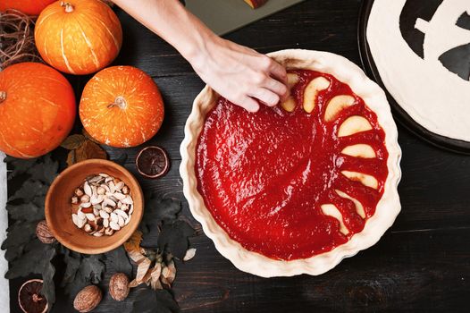 Chef cooks a pie for Halloween with a filling of pumpkin-strawberry jam and peaches