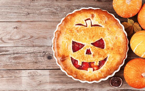 Delicious homemade pie for halloween with a filling of pumpkin-strawberry jam and peaches