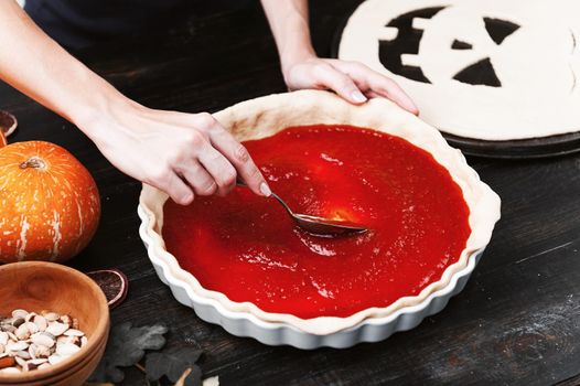 Chef cooks a pie for Halloween with a filling of pumpkin-strawberry jam and peaches