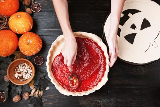 Chef cooks a pie for Halloween with a filling of pumpkin-strawberry jam and peaches