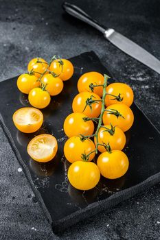 Bunch of yellow cherry tomato on a marble board. Black background. Top view.