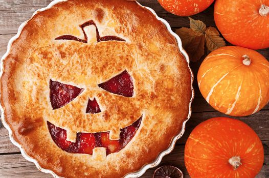 Delicious homemade pie for halloween with a filling of pumpkin-strawberry jam and peaches