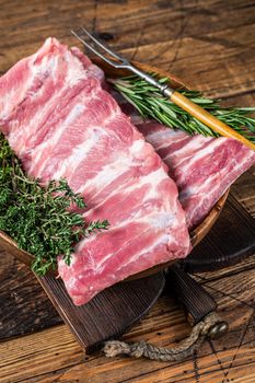 Raw pork spare ribs in wooden plate witn meat fork. wooden background. Top view.