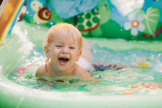 child plays in the pool. Little girl in the pool, smiling child.