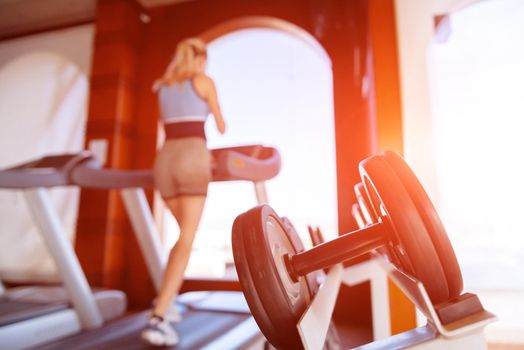 girl on the morning run on the treadmill in the gym in front of a large window on the background of the sea