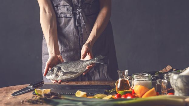 woman chef preparing fresh raw dorado fish