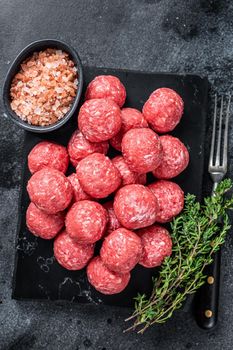 Raw meatballs from minced beef and pork meat with thyme. Wooden background. Top view.