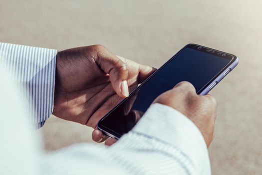 Very close-up view of black hands using mobile phone outdoors.