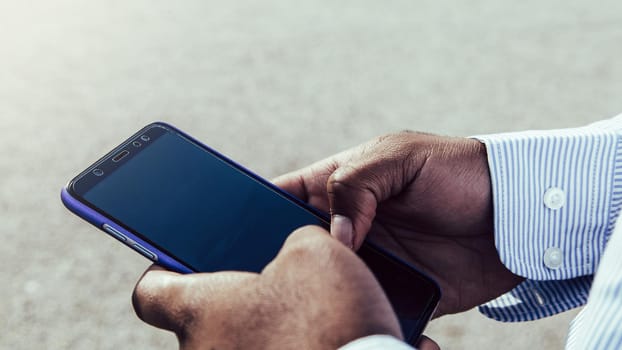 Very close-up view of black ethnicity hands using mobile phone outdoors.