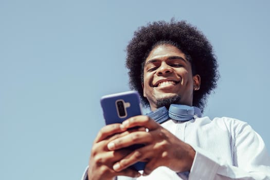 Happy young african american man using smartphone and smiling