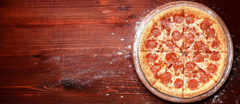 fresh american pizza on wooden table with space for text