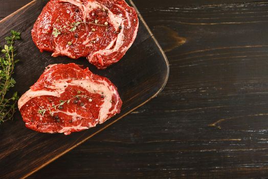 two raw marbled beef steaks in olive oil and spices ready for frying. dinner party concept