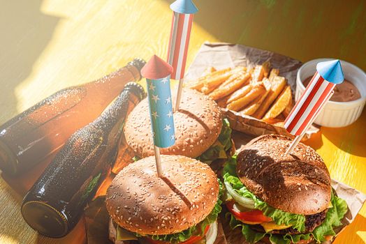 three fresh and juicy burgers with American flag-style fireworks inserted into them. bbq concept picnic to celebrate independence day