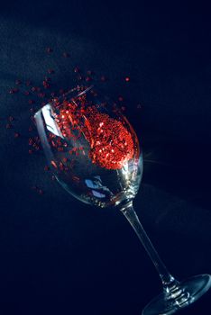 concept spilled red wine. end of the party. a glass of wine lying on a table in it red stars symbolizing spilled wine