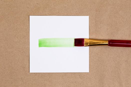 Paintbrush with smear of green paint. Smear of vivid green paint from brush on a piece of white paper
