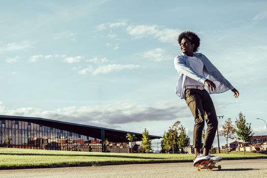 Young dark skinned man skating in modern park, copy space