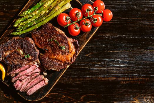 Dinner for two juicy delicious steaks, asparagus with parmesan and vegetables.