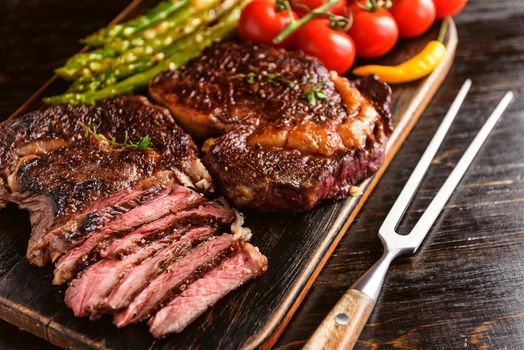 Dinner for two juicy delicious steaks, asparagus with parmesan and vegetables.