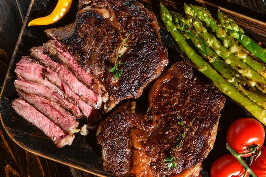 Dinner for two juicy delicious steaks, asparagus with parmesan and vegetables.