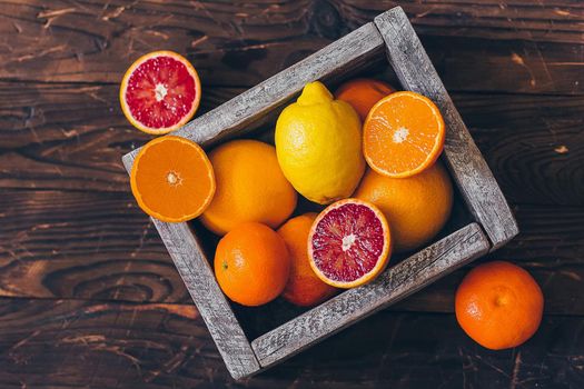 Juicy whole lemons, oranges and grapefruits and freshly cut half on rustic wooden background. Top view