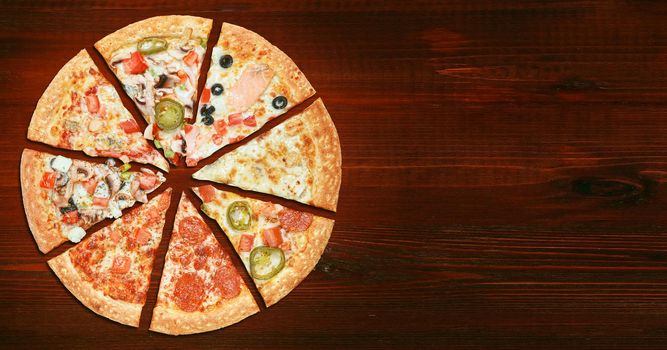 mix of eight different pizzas on a wooden background. menu concept of choice and diversity