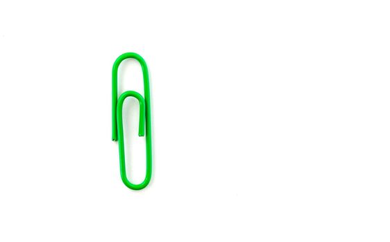 Green paper clip isolated on white background. Close up and top view