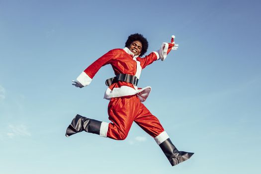 black ethnicity santa claus jumping with excitement and smiling to the camera
