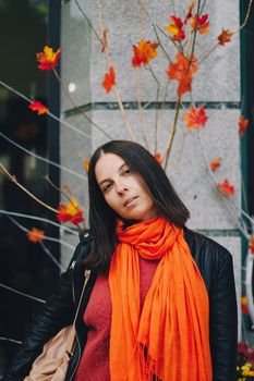Portrait of a happy woman in bright orange scarf in the city