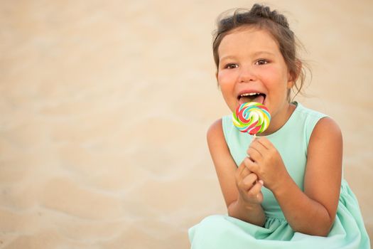 Cute little girl with big colorful lollipop. Child eating sweet candy bar. Sweets for young kids. Summer outdoor fun