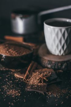 Chocolate bar pieces with cocoa powder. Cup of hot chocolate on dark background.