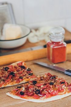 Fresh pizza with olives, cheese and bacon on kitchen table closeup